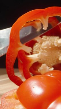 Kırmızı dolma biber halkalara bölünmüş. Kamera onların arasından uçuyor gibi görünüyor. Makro. Dikey video Sosyal Ortamı