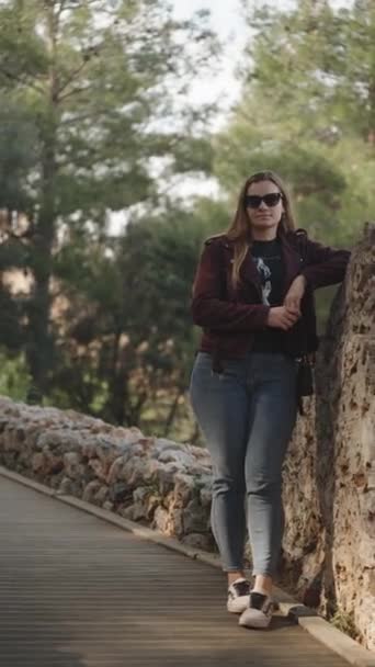 Молодая Женщина Парке Деревянной Дороге Прислонившаяся Старой Каменной Стене Вертикальное — стоковое видео