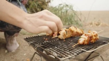 Kadınlar tahta çubuklarda tavuk eti pişirir, sahilde piknik yaparlar. Taşınabilir barbekü.