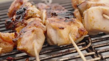 Tahta çubuklardaki tavuk eti ızgarada pişiriliyor, yakın plan.