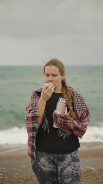 바람에서 벗어난 그녀의 머리카락을 여자가 바다와 날씨의 배경에 온도에서 마신다 — 비디오