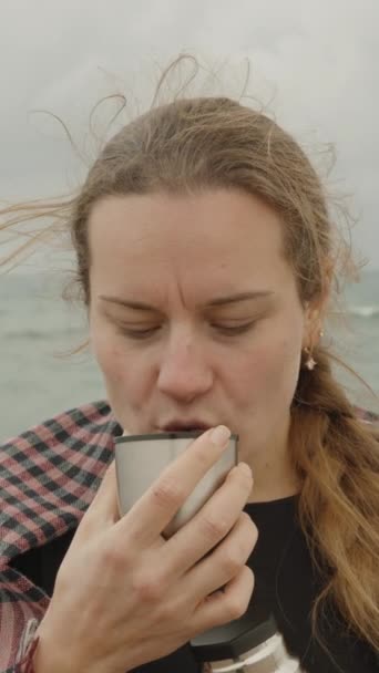 バーティカルビデオ 海の背景 曇った日にお茶を飲んでいる平野の若い女性の肖像画 — ストック動画