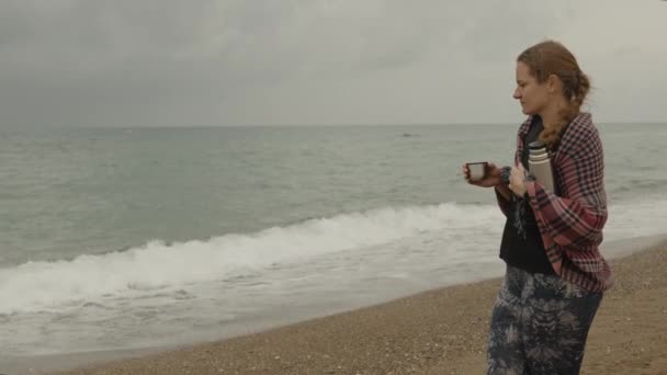 Облачный День Море Молодая Женщина Держит Кружку Чая Термоса Смотрит — стоковое видео
