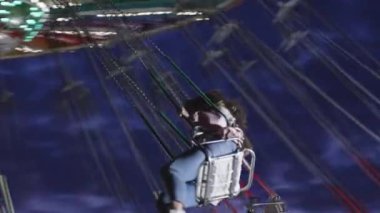 Genç bir kadın gece geç saatlerde atlıkarıncaya biner. Arkadaki dağlar, ağır çekim..