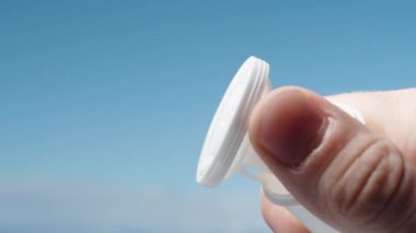 Mavi gökyüzüne karşı beyaz bir vitamin kavanozu açıp kapadım.