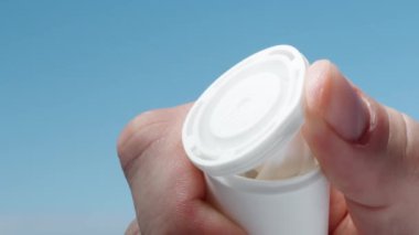 Dolgun vitamin haplarıyla dolu beyaz bir kavanoz açıp boşaltıyorum. Yakın plan..