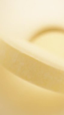 Beyaz kavanozun içinde sarı haplar var. Siyah arka planda beyaz bir masa. Dolly Slider aşırı yakın çekim. Dikey video.