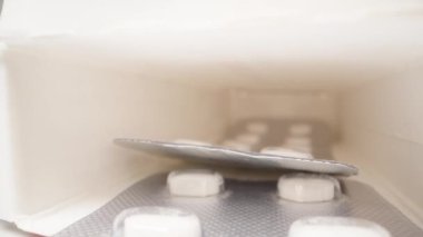 Oval tabletlerle dolu iki paketin içinde bir karton kutu. Beyaz arka planda izole edin. Dolly kaydırıcı aşırı yakın çekim.