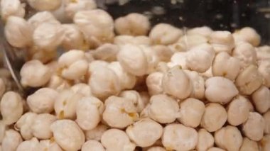 Nohut, suyla dolu, kaşıkla karıştırılmış, siyah arka planda ağır çekim. Yakın plan..