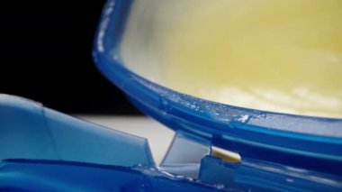 Parmağımla mavi bir kavanozdan vazelin alıyorum, siyah bir arka planda. Dolly kaydırıcı aşırı yakın çekim.