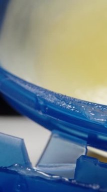 Parmağımla mavi bir kavanozdan vazelin alıyorum, siyah bir arka planda. Dolly Slider aşırı yakın çekim. Dikey video.