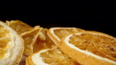 Siyah arka planda kurutulmuş portakal dilimleri. Dolly kaydırıcı aşırı yakın çekim.