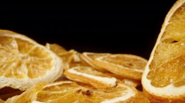 Kurutulmuş portakal dilimleri masaya saçılmış, kamera aralarına kayıyor, makro..
