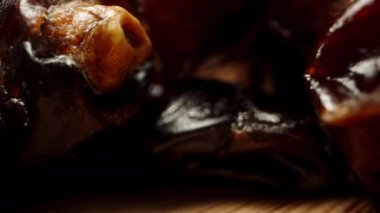 Ahşap bir masada kurumuş hurmalar ve siyah bir arka plan. Dolly kaydırıcı aşırı yakın çekim.