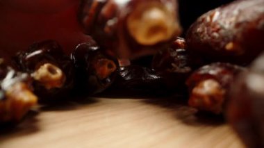 Ahşap bir masanın üzerinde kurumuş tarihler, kamera ilerlerken onları elimde inceliyorum. makro yakınlaştırma.