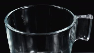 Şeffaf cam bardağa bir çikolata topu koydum. Siyah arkaplanda yakın plan.