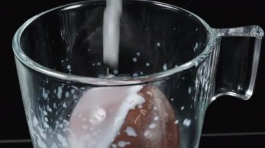 Erimesi için çikolatalı topun üzerine sıcak süt döküyorum. Sıçramalar, yakın çekim..