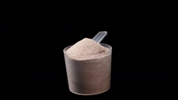 Διάφανο Κουτάλι Μέτρησης Σκόνη Πρωτεΐνης Σοκολάτας Περιστρέφεται Μαύρο Φόντο — Αρχείο Βίντεο