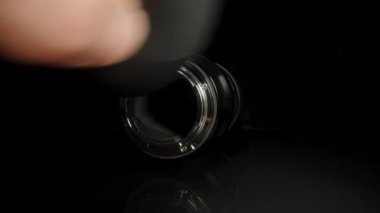 Objektifin tozunu siyah bir arka planda plastik bir ampulle patlatıyorum. Dolly kaydırıcı aşırı yakın çekim.