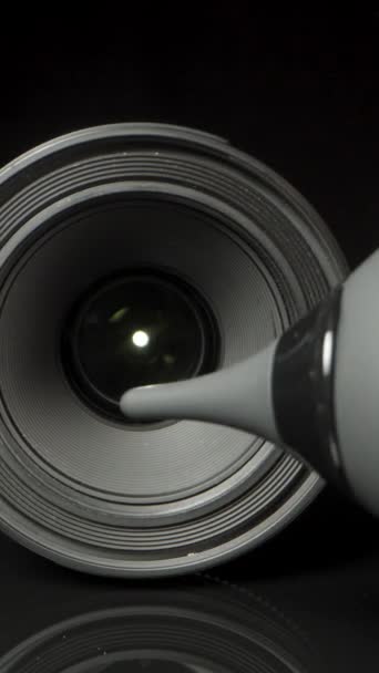 在黑色背景上的数码相机上的镜头 我用橡皮灯泡气泵的垂直视频把灰尘吹掉 — 图库视频影像