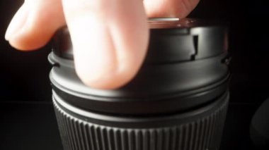 Kamera siyah arka planda yükselirken lensin kapağını kaldırıyorum ve plastik ampul hava pompasıyla tozunu alıyorum.