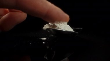 Parmağımı kaşığın üzerindeki beyaz toza sürüyorum ve siyah bir masaya serpiyorum..