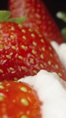 Çilekler çırpılmış krema tabakasının üzerine saçılmış. Dolly Slider aşırı yakın çekim. Dikey video.