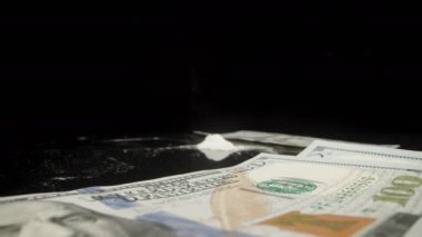 Yüz dolarlık banknotla beyaz tozu parçalara ayırıyorum. Kokain ve uyuşturucu konsepti, Dolly slider aşırı yakın çekim.