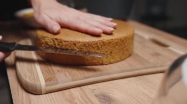 Kadın pastadaki sünger katmanlarını ikiye bölmek için bıçak kullanıyor..