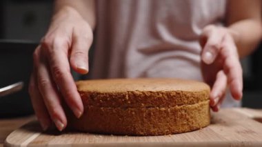 Kadın kek için sünger katmanını ikiye ayırıyor ve içerideki dokuyu gösteriyor..