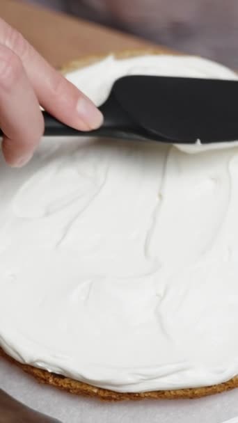 上から ペストリーシェフがケーキの層に白クリームを広げています バーティカルビデオ — ストック動画
