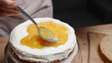 Pasta şefi, turuncu bir kompostosu pastanın üstüne yavaşça yayıyor..