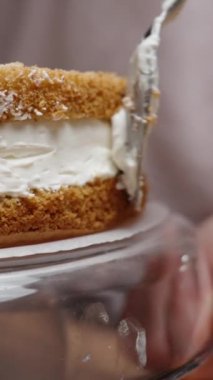 Pasta şefi pastayı çevirir ve kremayı pandispanya katmanları arasında dengeler. Ağır çekim. Dikey video.