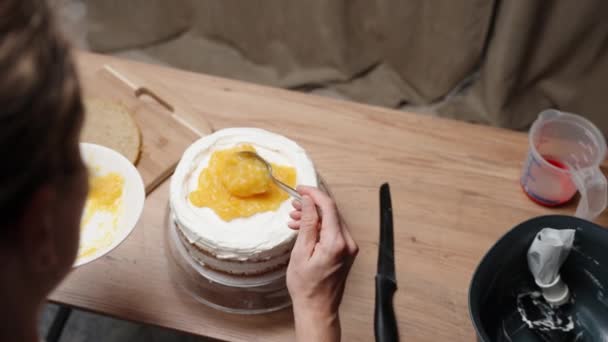 女性はケーキを準備しています サードパーソナルビュー 彼女はケーキの層の上にオレンジの充填を広げるように 遅い動きで — ストック動画
