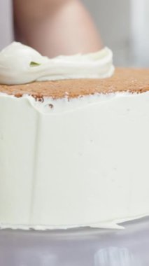 Pasta şefi pastanın kenarındaki kremayı yumuşatmak için geniş metal bir spatula kullanır. Dikey video.