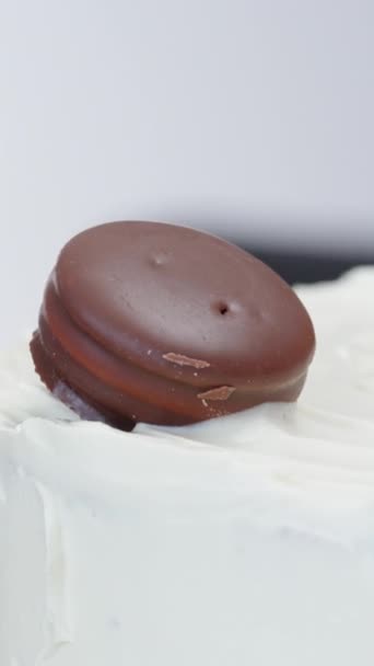 ペストリーシェフは スローモーションでホワイトクリームの上にチョコレートクッキーとマルベリーベリーを置くことによってケーキを飾ります バーティカルビデオ — ストック動画