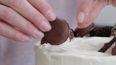 Pasta şefi süsleme olarak beyaz pastanın üstüne yuvarlak bir çikolatalı kurabiye koyar..