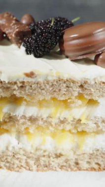 Üzerinde çikolata süslemeleri olan parlak güneş ışığı altında turuncu dolgulu bir pastanın yarısı. Dikey video.