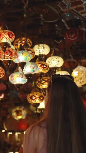 一位年轻女子走进一家土耳其纪念品店 天花板上挂着彩色玻璃做的吊灯 垂直录像 — 图库视频影像