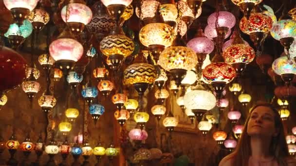 一位年轻女子正在检查挂在一家商店天花板上的色彩艳丽的土耳其古灯 — 图库视频影像