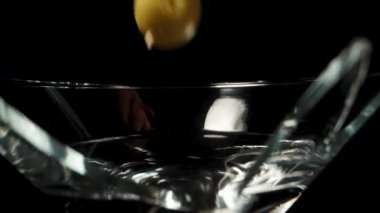 Kırık martini bardağında, kürdanın üzerine zeytinler düşüyor, ağır çekimde, dolly slider.