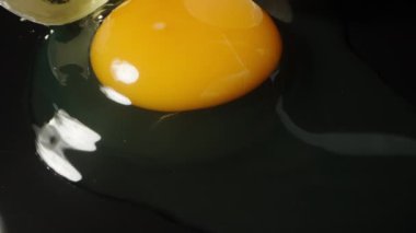 Siyah aynalı masa ve arka planda kırılmış bir tavuk yumurtasının yukarıdan görünüşü. Dolly kaydırıcı aşırı yakın çekim.