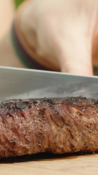 木製の切断板にナイフと 半分に牛肉ステーキを切りました クローズアップショット ミディアムドーネスです バーティカルビデオ — ストック動画