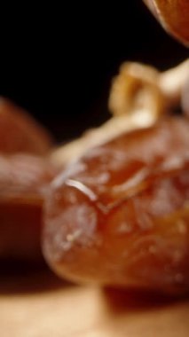 Kurumuş tarihler ahşap bir masanın üzerinde düzenlenir ve kamera aralarından süzülür. Dolly Slider aşırı yakın çekim. Dikey video.