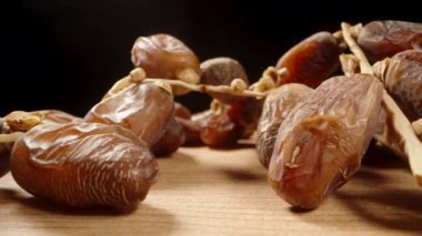 Kurumuş tarihler bir dalın üzerinde, tahta bir masanın üzerinde uzanıyor ve pürüzsüz bir şekilde ışığa çıkıyor..