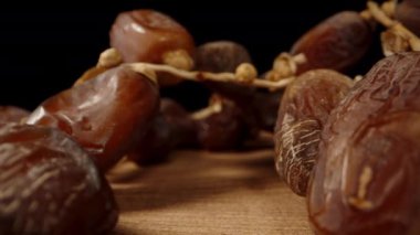 Kamera ahşap masada süzülüyor, kurumuş hurma dalları arasında, pürüzsüz ışıklandırmayla, makro bir kaydırak içinde..