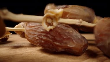 Kamera geriye doğru kayarken, kurumuş tarihleri masaya dallarla seriyorum, makro bir çekimle..