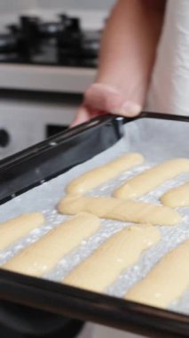 Ekler için choux pastası bir fırın tepsisine konur ve kadın onu fırına koyar. Ağır çekim. Dikey video.