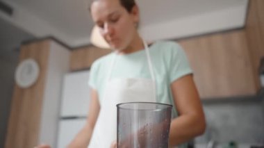 Beyaz önlüklü genç bir kadın mutfakta arta kalan nektarin parçalarını yiyor. Kamera açısı aşağıdan yukarıya bakıyor..