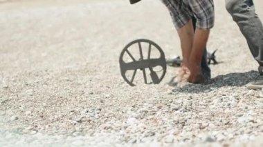 Plajda metal dedektörlü bir adam elleriyle taşları inceliyor. Bir şey buldu..